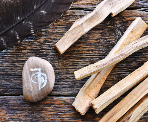 Une image supérieure de vue d’un symbole curatif de reiki et des bâtons de bavure de palo santo sur un dessus en bois foncé de table.